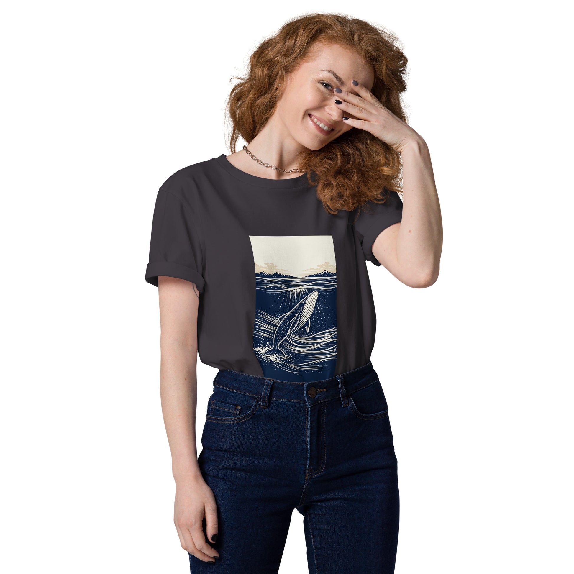 Lifestyle photo of Organic cotton whale graphic t shirt featuring a minimalist ocean illustration with rising whale and beige horizon sky. color: anthracite