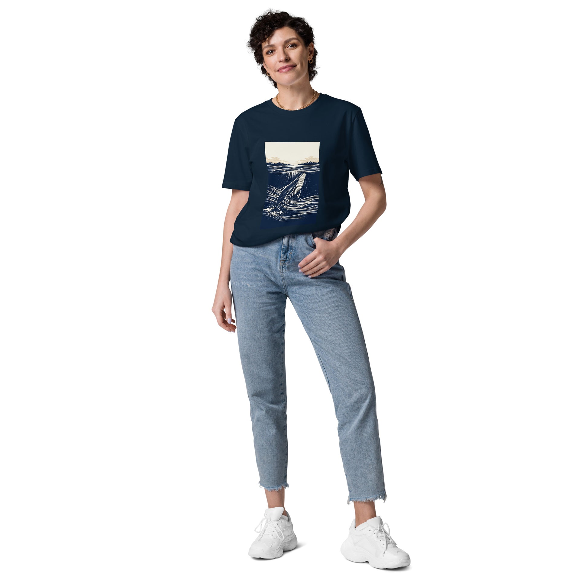 Lifestyle photo of Organic cotton whale graphic t shirt featuring a minimalist ocean illustration with rising whale and beige horizon sky. color: french navy