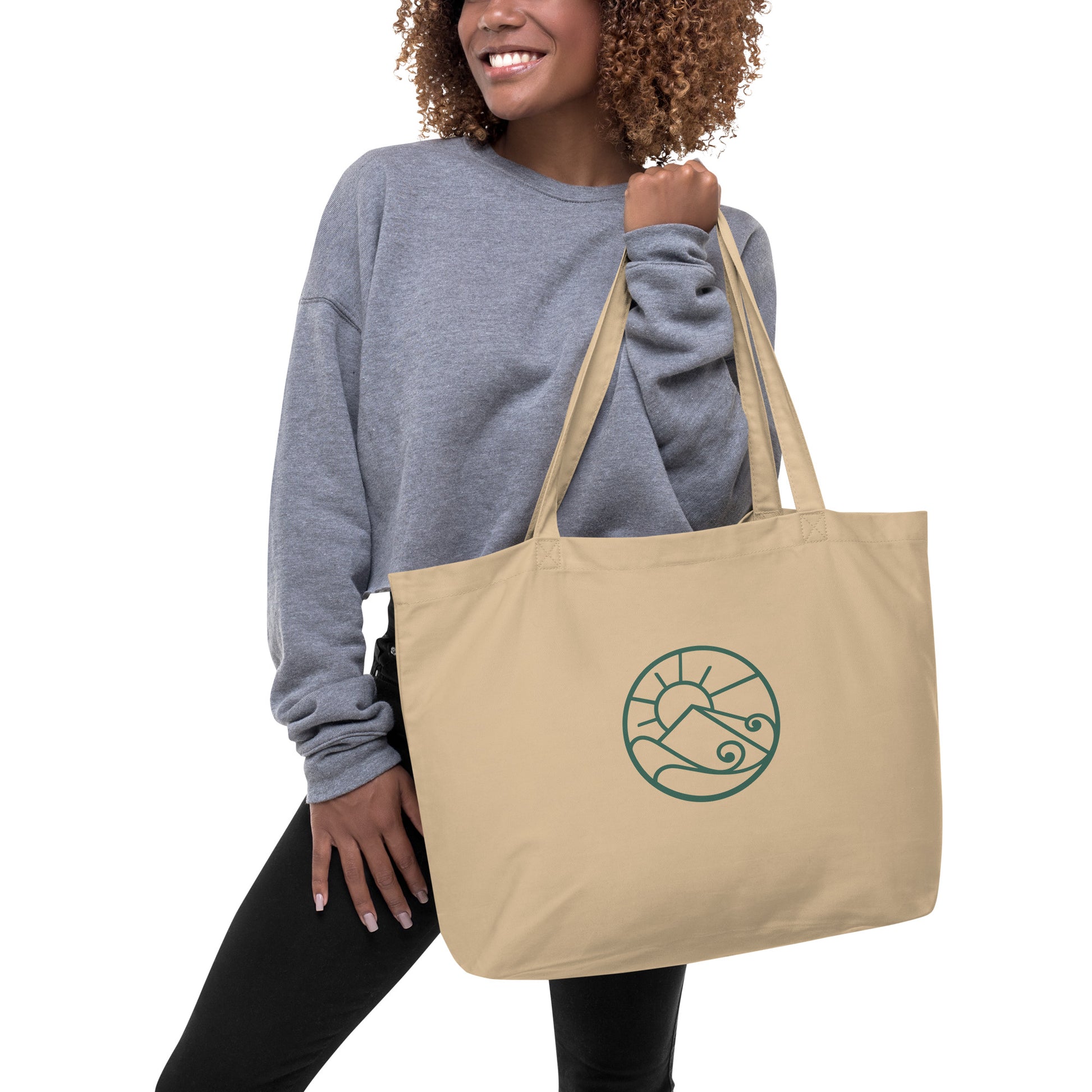 Lifestyle photo of Large organic cotton tote bag with green Gaia’s Harmony logo on natural canvas fabric