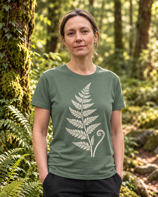 Woman wearing the Rooted organic cotton fern T-shirt in Green Bay, featuring a cream fern and fiddlehead design in an Irish woodland, designed by Gaia's Harmony. Color: green bay